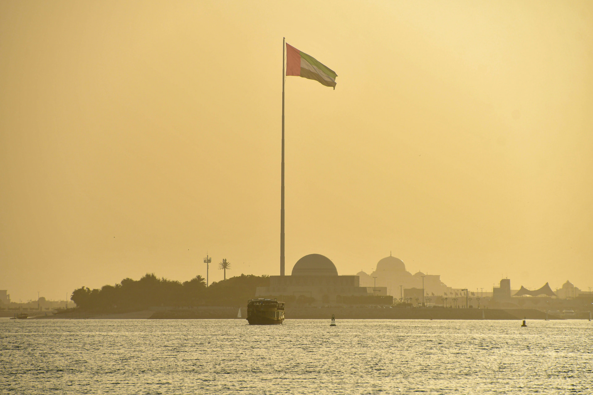 UAE flag above the Abu Dhabi waterfront at golden hour